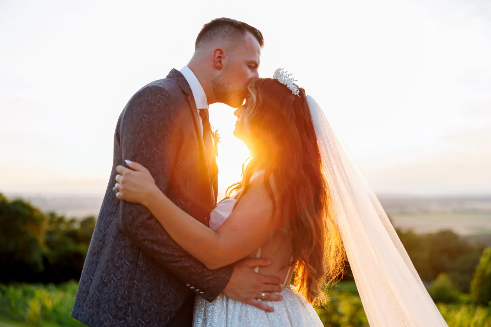 Couple kissing at golden hour with a flowing veil